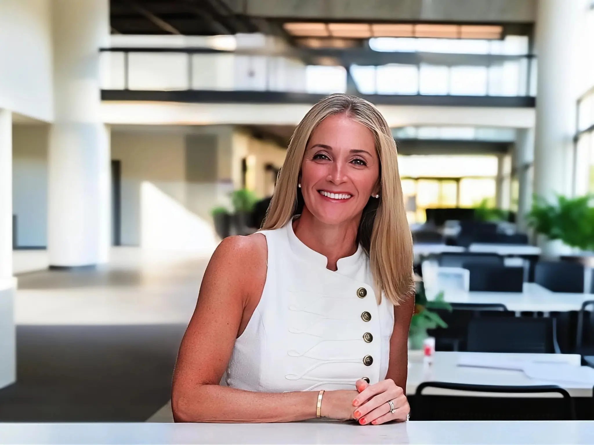 Alison LoPresti in a white sleeveless top in a bright modern office.